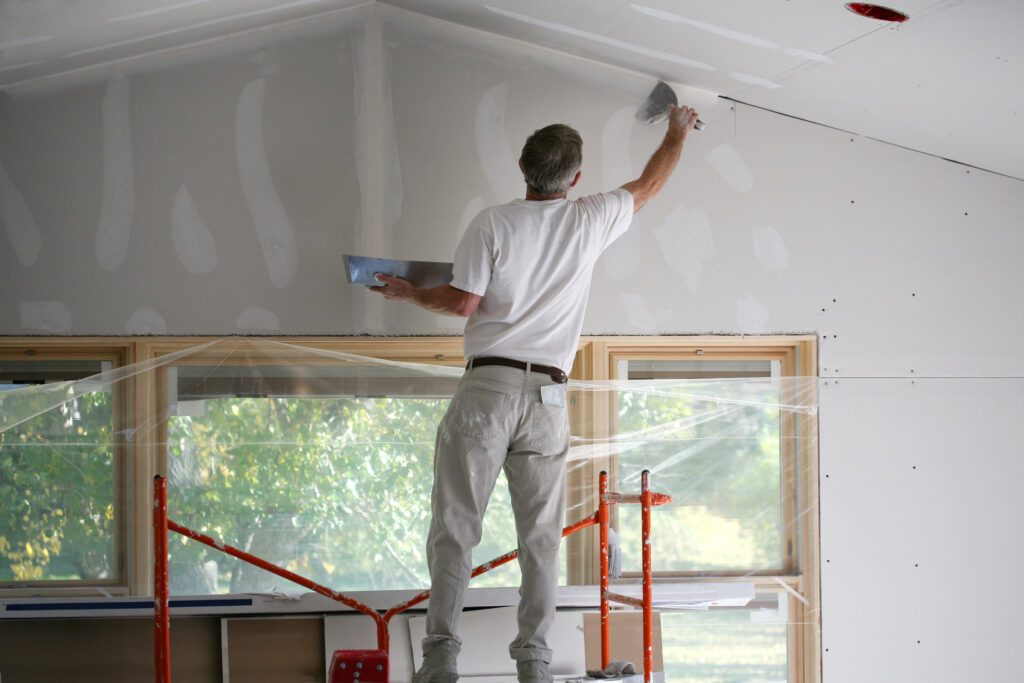 man plastering inside a property on a scaffold